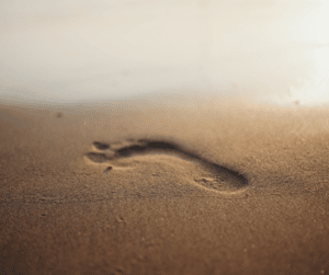 Green supply chain - a picture of a footprint on sand to represent the term "carbon footprint"