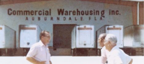 A view of a CWI warehouse with three men in front in the 1960s. CWI is a full-service logsitics company.